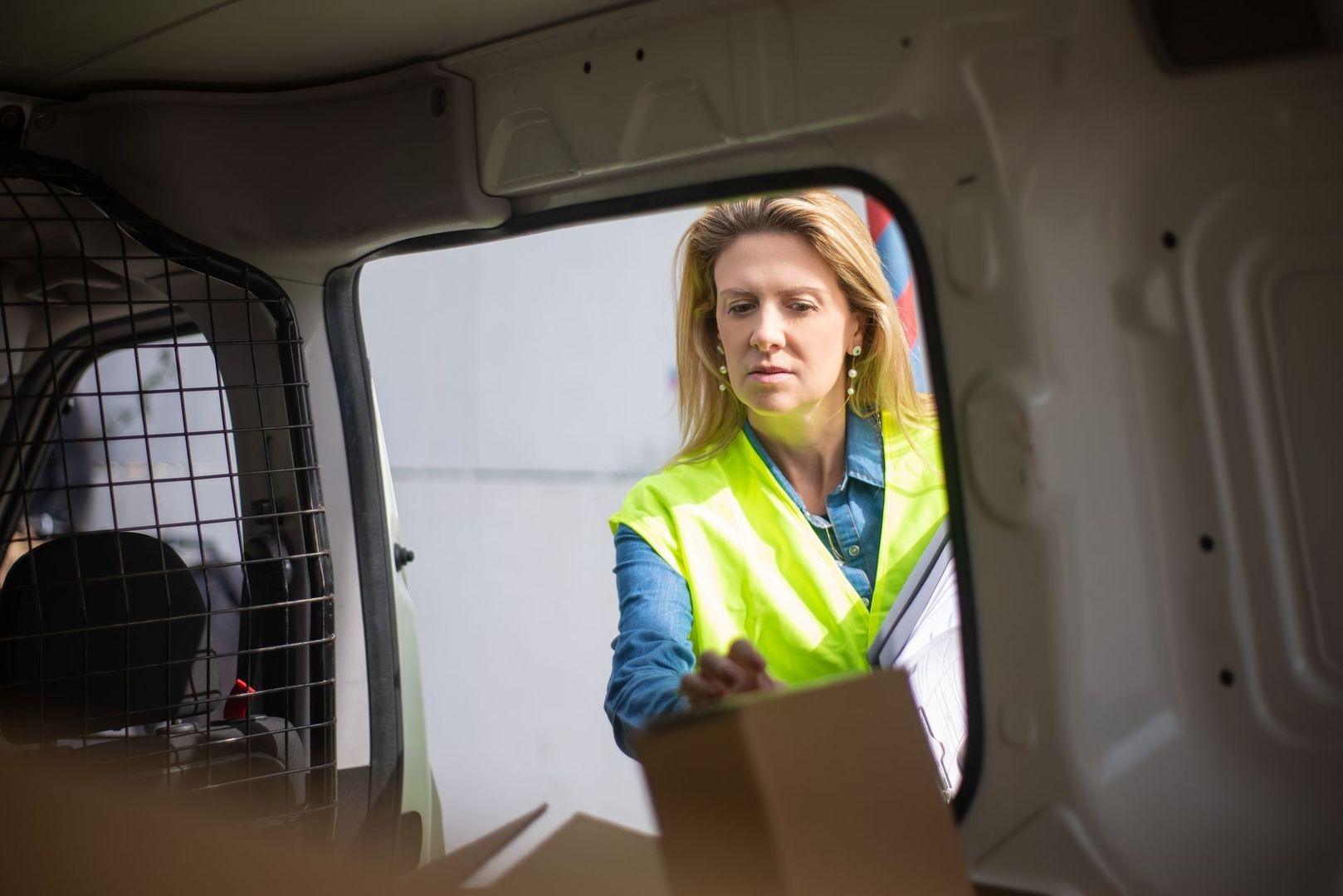Brevolycksarbetare i varselväst lämnar ett paket vid en skåpbil