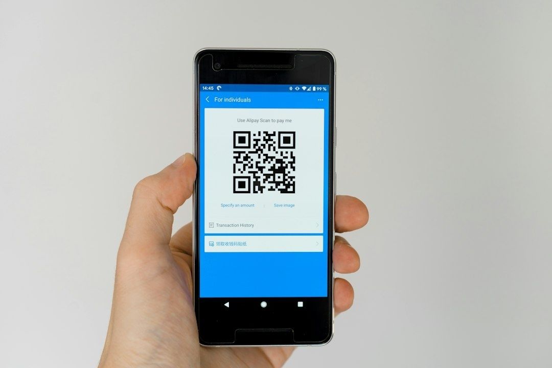 Hand håller en smartphone som visar en QR-kod för betalning